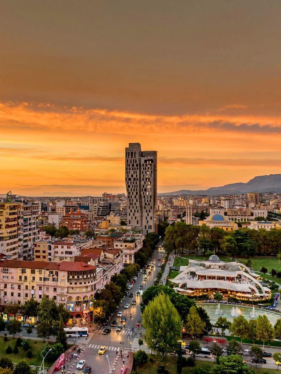 Tirana nga lart në perëndim të diellit, me Kullën Downtown One dhe Parkun Rinia